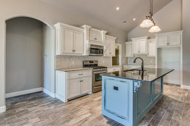 This is an example of a mid-sized traditional l-shaped open plan kitchen in Oklahoma City with a double-bowl sink, recessed-panel cabinets, white cabinets, granite benchtops, white splashback, ceramic splashback, stainless steel appliances, porcelain floors, with island and beige floor.