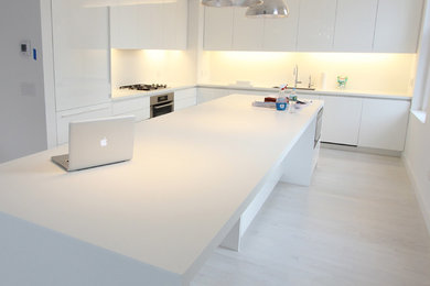 Inspiration for a large contemporary u-shaped eat-in kitchen in New York with flat-panel cabinets, white cabinets, white splashback, panelled appliances and with island.