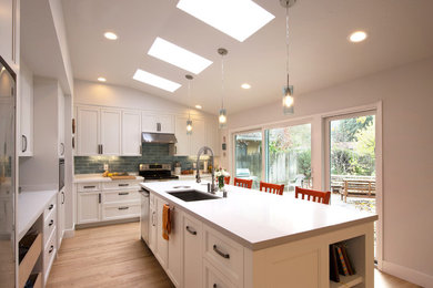 Inspiration for a mid-sized contemporary l-shaped kitchen in Sacramento with a single-bowl sink, recessed-panel cabinets, white cabinets, quartz benchtops, blue splashback, porcelain splashback, stainless steel appliances, light hardwood floors, with island and white benchtop.