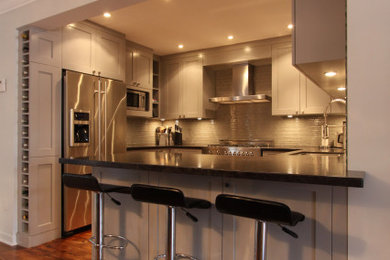 Example of a mid-sized transitional u-shaped medium tone wood floor and brown floor eat-in kitchen design in Toronto with a single-bowl sink, shaker cabinets, gray cabinets, granite countertops, gray backsplash, glass tile backsplash, stainless steel appliances, a peninsula and brown countertops