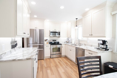 Mid-sized transitional u-shaped eat-in kitchen in Other with an undermount sink, shaker cabinets, white cabinets, quartz benchtops, stainless steel appliances, vinyl floors, no island, brown floor and beige benchtop.