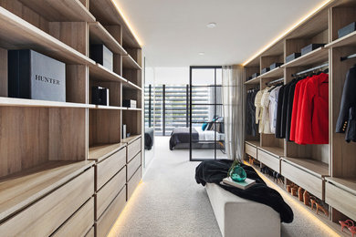 Large modern gender-neutral dressing room in Melbourne with light wood cabinets, carpet and grey floor.