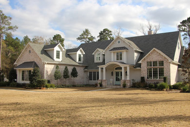Immagine della villa ampia multicolore a due piani con rivestimento in mattoni, tetto a capanna, copertura a scandole e tetto grigio