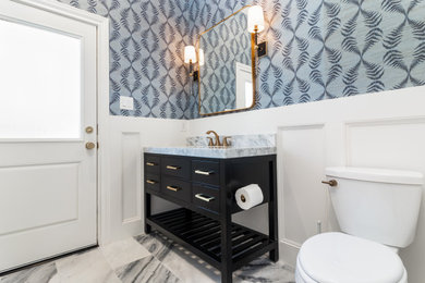 Mid-sized elegant marble floor and wall paneling powder room photo in Houston with a freestanding vanity
