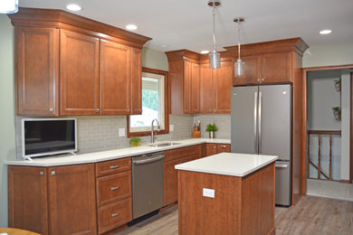 Small transitional l-shaped vinyl floor and brown floor eat-in kitchen photo in Other with an undermount sink, flat-panel cabinets, medium tone wood cabinets, quartz countertops, gray backsplash, glass tile backsplash, stainless steel appliances, an island and gray countertops