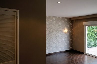 Idée de décoration pour une chambre parentale design de taille moyenne avec un mur beige, parquet foncé, aucune cheminée, un sol marron et du papier peint.