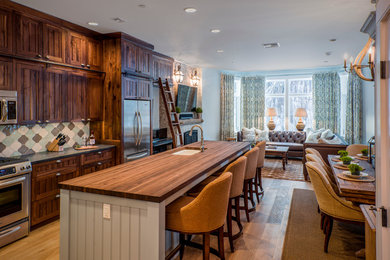 Open concept kitchen - large rustic galley light wood floor and brown floor open concept kitchen idea in Burlington with an island, an undermount sink, shaker cabinets, medium tone wood cabinets, wood countertops, multicolored backsplash, mosaic tile backsplash and stainless steel appliances
