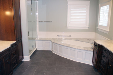 Photo of a large traditional master bathroom in New York with beaded inset cabinets, dark wood cabinets, an undermount tub, a corner shower, a two-piece toilet, white tile, ceramic tile, blue walls, porcelain floors, an undermount sink, marble benchtops, grey floor, a hinged shower door and grey benchtops.