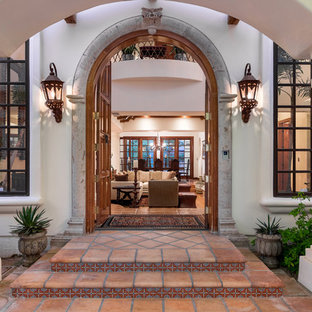 Создайте стильный интерьер: входная дверь среднего размера в средиземноморском стиле с белыми стенами, полом из терракотовой плитки и двустворчатой входной дверью - последний тренд