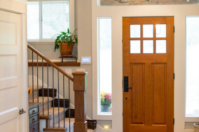 Modelo de distribuidor de estilo de casa de campo de tamaño medio con paredes beige, suelo de madera oscura, puerta simple, puerta naranja, suelo marrón y machihembrado