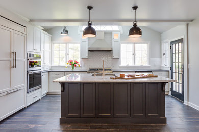 Inspiration for a large transitional l-shaped porcelain tile enclosed kitchen remodel in New York with an undermount sink, flat-panel cabinets, white cabinets, granite countertops, white backsplash, ceramic backsplash, stainless steel appliances and an island