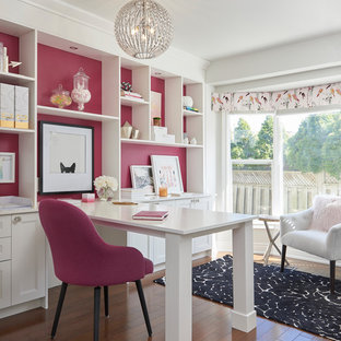 Photo of a transitional craft room in Toronto with pink walls, medium hardwood floors, no fireplace, a built-in desk and brown floor.