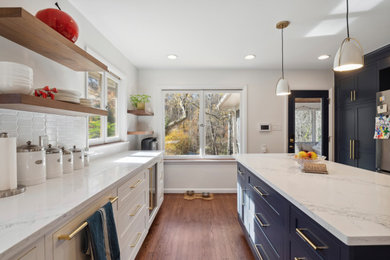 Inspiration for a mid-sized 1950s galley dark wood floor and brown floor eat-in kitchen remodel in Wilmington with a drop-in sink, flat-panel cabinets, blue cabinets, quartz countertops, white backsplash, ceramic backsplash, stainless steel appliances, an island and white countertops