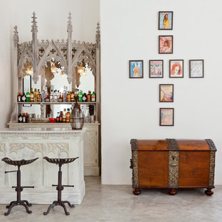 ロンドンの中サイズのエクレクティックスタイルのおしゃれな着席型バー (白いキャビネット、ミラータイルのキッチンパネル、オープンシェルフ、大理石カウンター、コンクリートの床、シンクなし) の写真