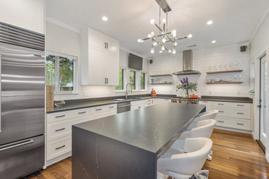 Example of a mid-sized trendy l-shaped medium tone wood floor and brown floor eat-in kitchen design in Austin with an undermount sink, shaker cabinets, white cabinets, quartz countertops, white backsplash, shiplap backsplash, stainless steel appliances, an island and gray countertops