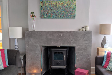 Example of a trendy medium tone wood floor and brown floor living room design in New York with gray walls, a wood stove and a concrete fireplace