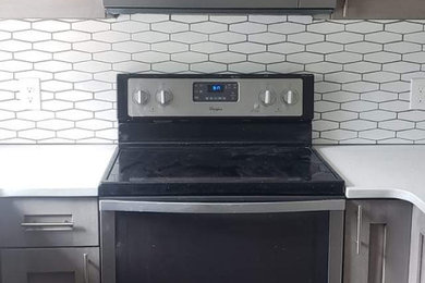 Enclosed kitchen - small cottage u-shaped slate floor and gray floor enclosed kitchen idea in Other with an undermount sink, shaker cabinets, light wood cabinets, quartz countertops, white backsplash, subway tile backsplash, stainless steel appliances and white countertops