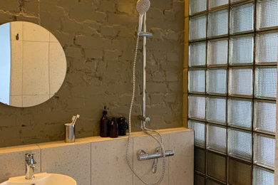 モスクワにあるインダストリアルスタイルのおしゃれな浴室 (洗い場付きシャワー、ベージュのタイル、磁器タイル、緑の壁、磁器タイルの床、壁付け型シンク、ベージュの床、洗面台1つ、レンガ壁) の写真