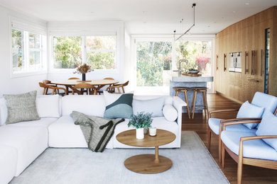 Small midcentury open concept living room in Auckland with a home bar, white walls, medium hardwood floors, no fireplace, a wall-mounted tv and turquoise floor.