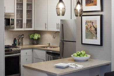 Example of a small trendy u-shaped slate floor and gray floor kitchen design in New York with an undermount sink, shaker cabinets, white cabinets, quartz countertops, white backsplash, ceramic backsplash, stainless steel appliances and beige countertops