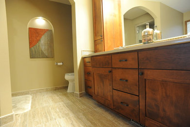 Large traditional master bathroom in Milwaukee with an integrated sink, shaker cabinets, medium wood cabinets, solid surface benchtops, a two-piece toilet, multi-coloured tile, beige walls and porcelain floors.