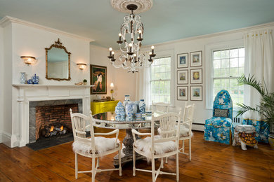 Inspiration for a large eclectic separate dining room in New York with white walls, medium hardwood floors, a standard fireplace, a stone fireplace surround and brown floor.