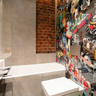 Idee per una piccola stanza da bagno per bambini industriale con ante lisce, ante gialle, zona vasca/doccia separata, WC sospeso, piastrelle grigie, piastrelle in gres porcellanato, pavimento in cemento, lavabo integrato, top in superficie solida, pavimento grigio, porta doccia scorrevole, top bianco, toilette, un lavabo, mobile bagno sospeso e pareti in mattoni