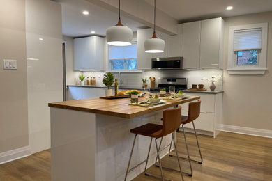 Eat-in kitchen - mid-sized modern l-shaped vinyl floor and brown floor eat-in kitchen idea in Ottawa with a single-bowl sink, flat-panel cabinets, white cabinets, quartzite countertops, gray backsplash, porcelain backsplash, stainless steel appliances, an island and gray countertops