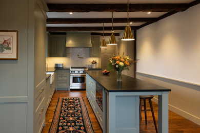 Kitchen - traditional l-shaped medium tone wood floor, brown floor and exposed beam kitchen idea in Burlington with a farmhouse sink, shaker cabinets, green cabinets, soapstone countertops, white backsplash, subway tile backsplash, stainless steel appliances and black countertops