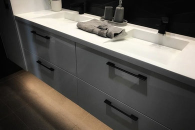 Photo of a mid-sized modern 3/4 bathroom in Geelong with white cabinets, black tile, solid surface benchtops and white benchtops.