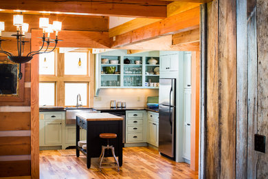 Mid-sized mountain style u-shaped medium tone wood floor kitchen photo in Charlotte with a farmhouse sink, recessed-panel cabinets, granite countertops, stainless steel appliances and an island