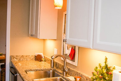 Example of a mid-sized classic l-shaped dark wood floor eat-in kitchen design in Chicago with an undermount sink, raised-panel cabinets, white cabinets, granite countertops, stainless steel appliances and a peninsula