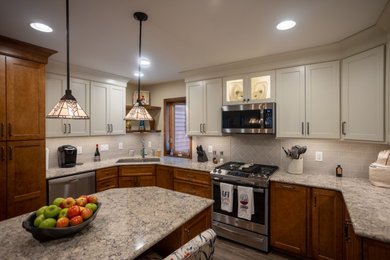 Example of a mid-sized classic u-shaped dark wood floor and brown floor enclosed kitchen design in Cincinnati with a drop-in sink, shaker cabinets, white cabinets, granite countertops, subway tile backsplash, stainless steel appliances, an island, multicolored countertops and gray backsplash
