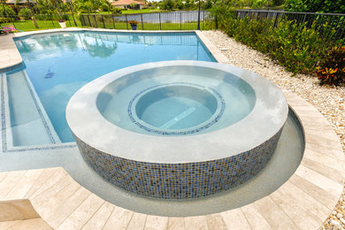 Inspiration for a contemporary backyard custom-shaped pool in Miami with a hot tub and natural stone pavers.