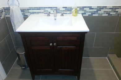 Bathroom - mid-sized modern 3/4 gray tile and porcelain tile porcelain tile and gray floor bathroom idea in Los Angeles with recessed-panel cabinets, dark wood cabinets, an integrated sink and quartz countertops