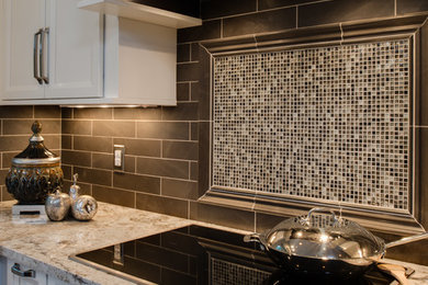Inspiration for a mid-sized transitional l-shaped medium tone wood floor eat-in kitchen remodel in Detroit with an undermount sink, recessed-panel cabinets, white cabinets, granite countertops, gray backsplash, stone tile backsplash, stainless steel appliances and an island