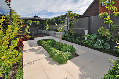 Inspiration for a mid-sized contemporary backyard patio in Christchurch with natural stone pavers and no cover.