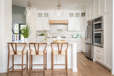 Inspiration for a mid-sized transitional l-shaped light wood floor and brown floor eat-in kitchen remodel in Other with a farmhouse sink, shaker cabinets, white cabinets, quartz countertops, yellow backsplash, porcelain backsplash, stainless steel appliances, an island and white countertops