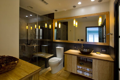 Inspiration for a mid-sized contemporary master porcelain tile and black tile bamboo floor and yellow floor walk-in shower remodel in Raleigh with a vessel sink, light wood cabinets, wood countertops, a two-piece toilet, yellow walls, flat-panel cabinets, a hinged shower door and yellow countertops