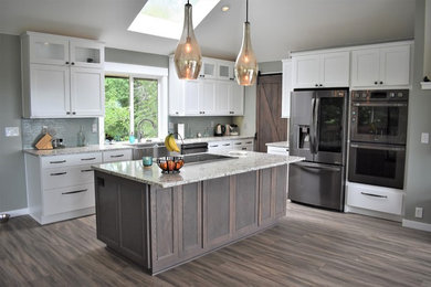 Inspiration for a large arts and crafts eat-in kitchen in Seattle with a farmhouse sink, shaker cabinets, white cabinets, quartz benchtops, green splashback, glass tile splashback, stainless steel appliances, vinyl floors, with island, multi-coloured floor and multi-coloured benchtop.