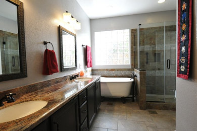Example of a mid-sized mountain style master porcelain tile porcelain tile claw-foot bathtub design in Las Vegas with an undermount sink, recessed-panel cabinets, brown cabinets, granite countertops, a two-piece toilet and gray walls