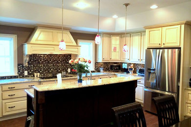 Inspiration for a large timeless u-shaped porcelain tile eat-in kitchen remodel in Austin with an undermount sink, raised-panel cabinets, beige cabinets, granite countertops, multicolored backsplash, mosaic tile backsplash, stainless steel appliances and an island