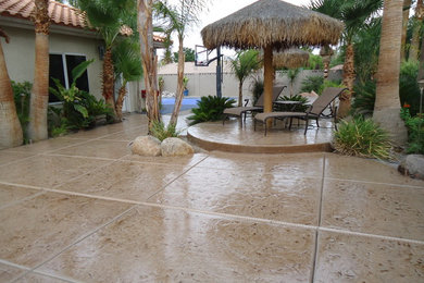 Large tropical backyard partial sun garden in Las Vegas with concrete pavers for summer.