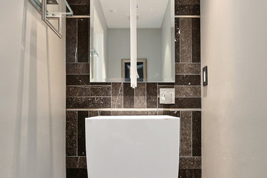Photo of a small contemporary powder room in Denver with a pedestal sink, gray tile, limestone floors and limestone.