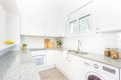 Modelo de cocinas en U abovedado y gris y blanco mediterráneo pequeño abierto sin isla con fregadero de doble seno, armarios con rebordes decorativos, puertas de armario blancas, encimera de granito, salpicadero metalizado, suelo laminado y suelo marrón
