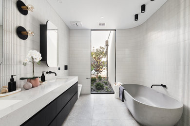 Photo of a mid-sized contemporary bathroom in Melbourne with black cabinets, a freestanding tub, a wall-mount toilet, white tile, matchstick tile, marble benchtops, white benchtops, a double vanity and a floating vanity.