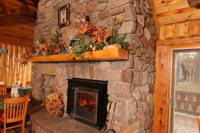 Enclosed dining room - mid-sized rustic light wood floor enclosed dining room idea in Other with brown walls, a standard fireplace and a stone fireplace