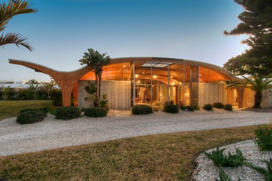 Example of a mid-sized 1950s beige one-story glass flat roof design in Tampa