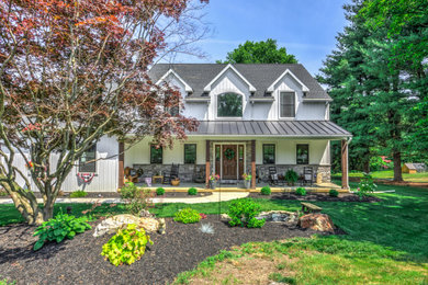 Inspiration for a country white two-story vinyl and board and batten house exterior remodel with a mixed material roof