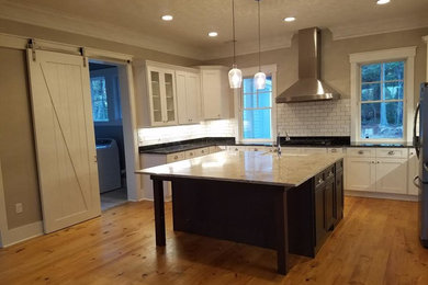 Eat-in kitchen - mid-sized craftsman u-shaped light wood floor eat-in kitchen idea in Charleston with a farmhouse sink, shaker cabinets, white cabinets, marble countertops, white backsplash, subway tile backsplash, stainless steel appliances and an island